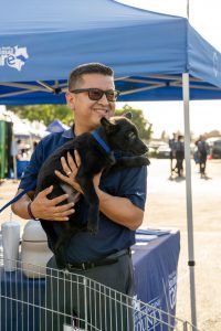 Jesse Armendarez holding a dog on the side of an Animal Care tent