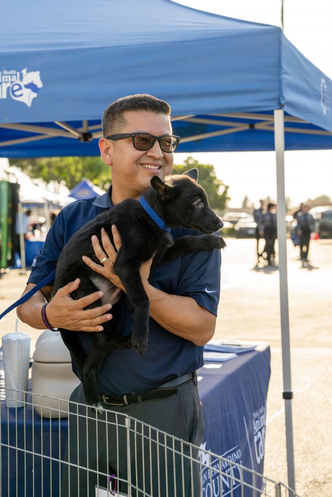 Jesse Armendarez holding a dog on the side of an Animal Care tent
