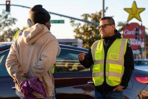 Jesse Armendarez outside in a high visibility vest speaking to a man with the Carl's Jr sign in the background.